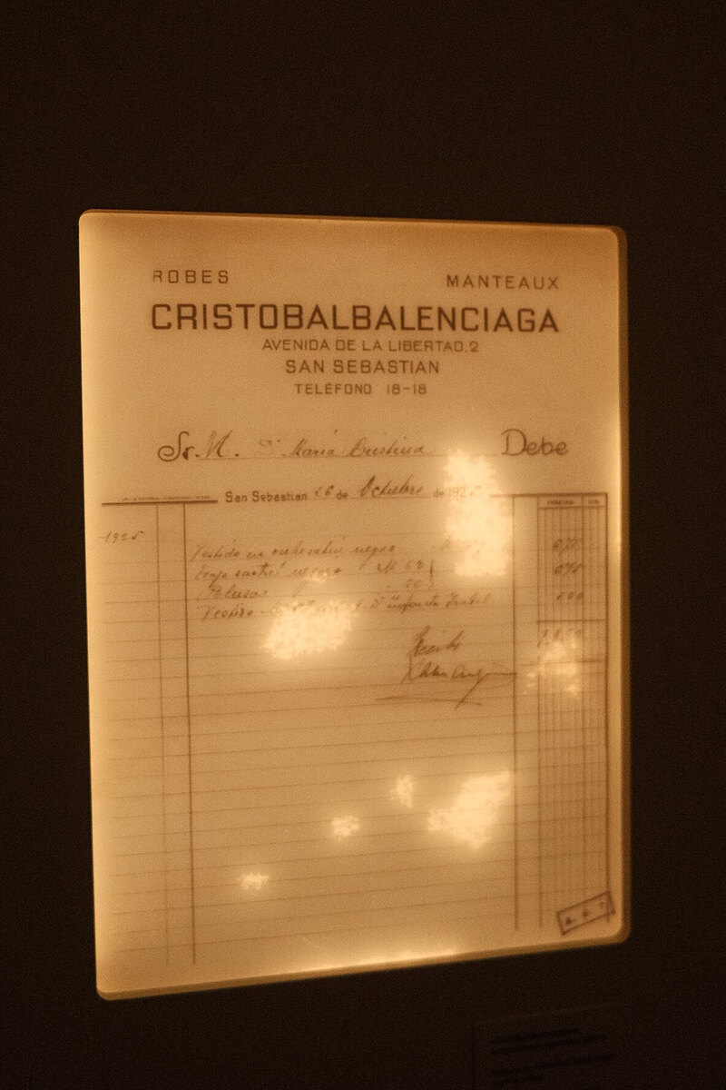 Glowing display of a historic handwritten Balenciaga invoice with printed header and cursive entries.